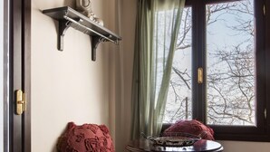 Una stanza con una panca, un tavolino, una statua di Buddha e una finestra con tende.
