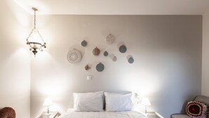 A bedroom with a bed, bedside tables, a chair, and a hanging light fixture. - Stagiates Guest House Room 3 (Μακρινίτσα)