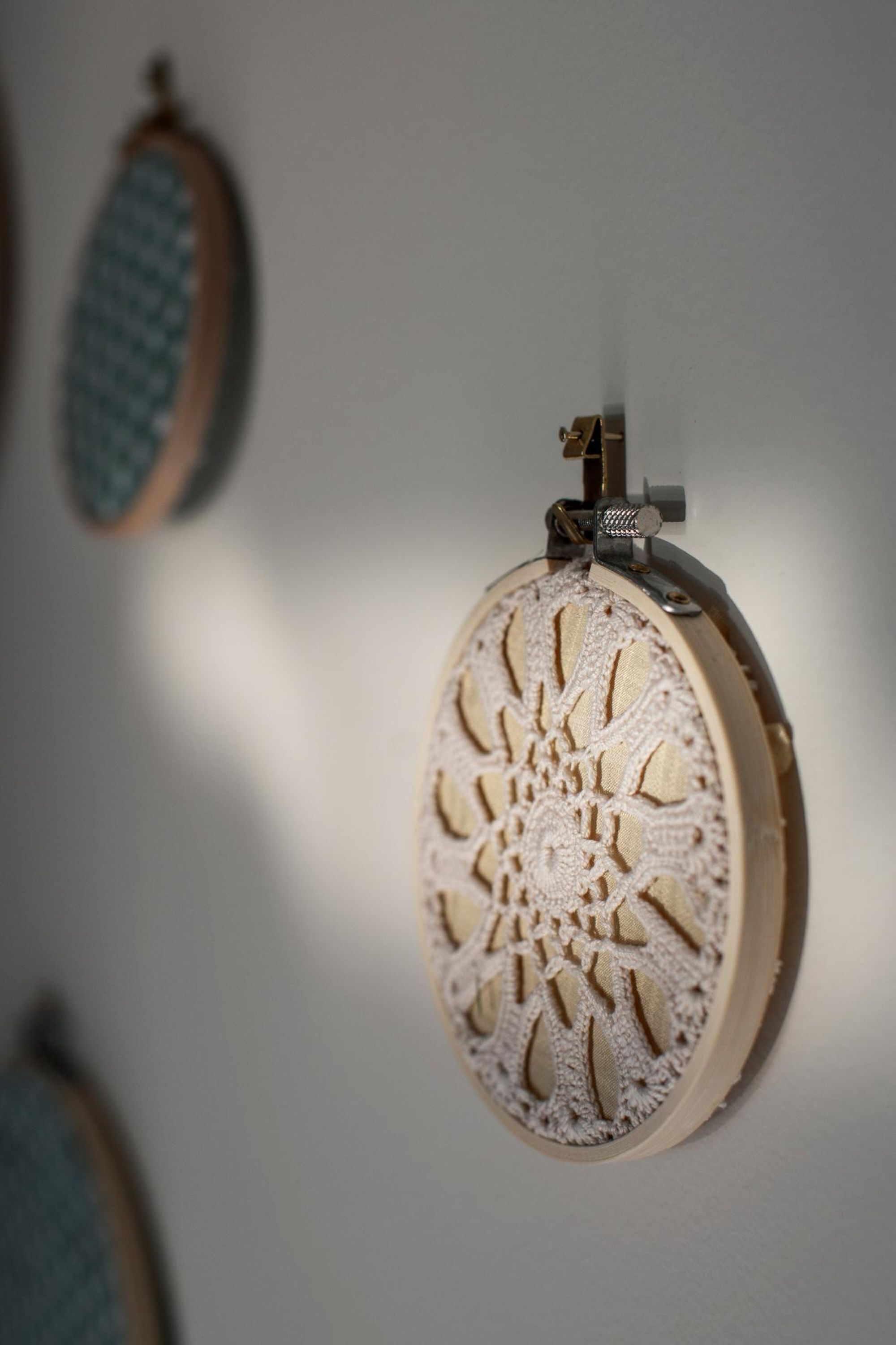 Un mur orné d’un cercle à broder et d’une aiguille.