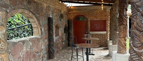 A rustic interior with exposed brick walls, a tiled floor, and wooden furniture.