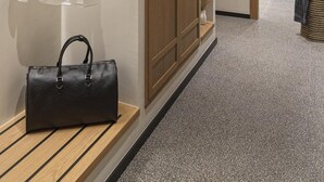 Un couloir avec un plafond en bois, une chemise blanche suspendue, un sac à main noir et un meuble en bois doté d’étagères.