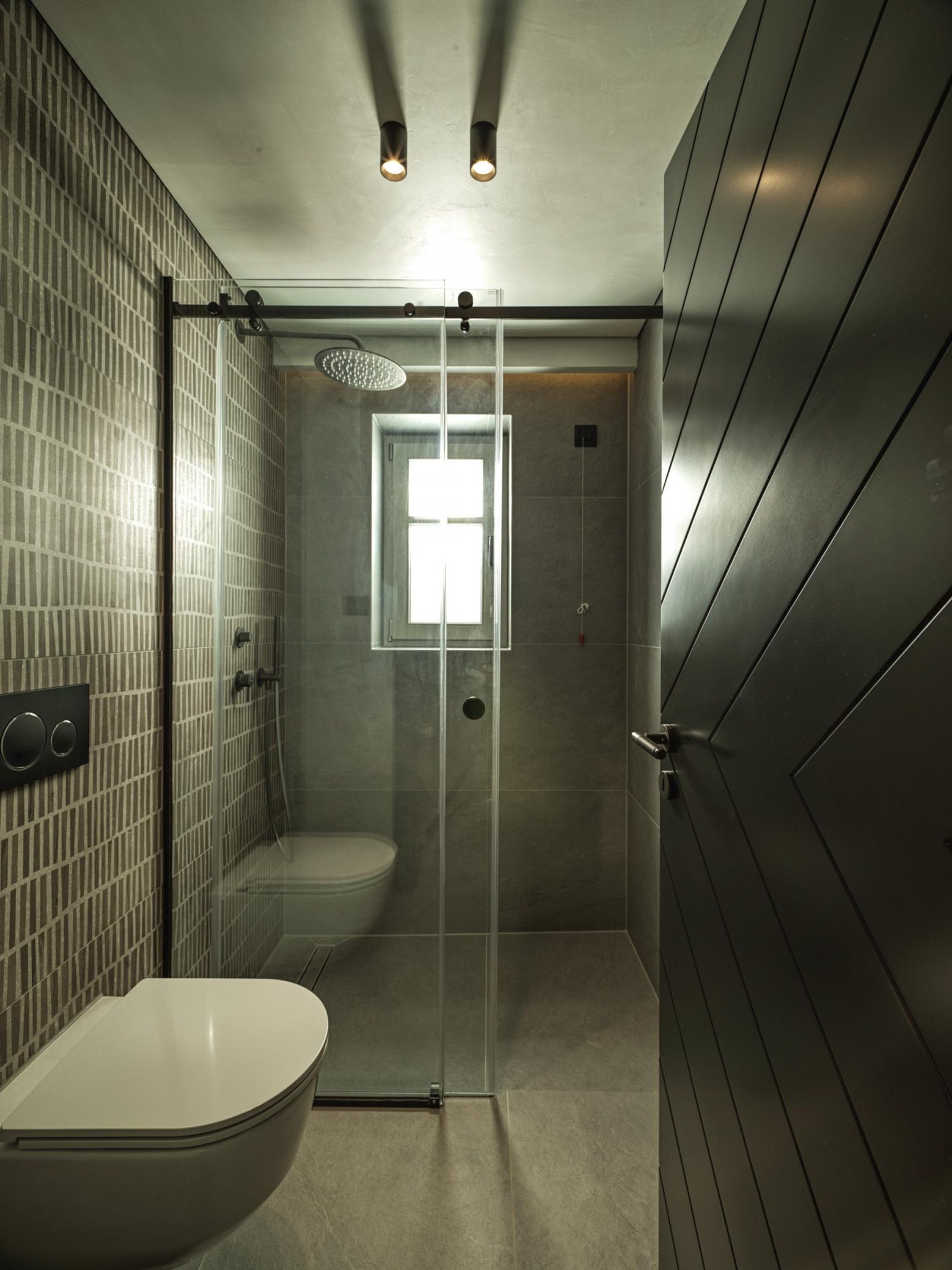 Un baño moderno con ducha acristalada, inodoro y lavamanos.