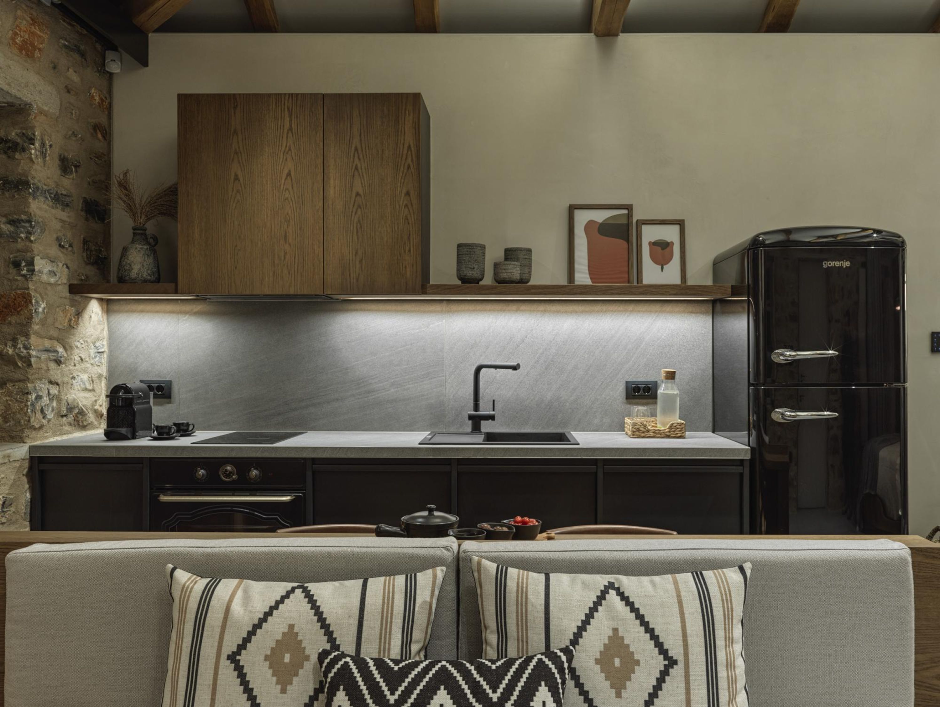 Una cocina moderna con armarios oscuros, un protector contra salpicaduras de acero inoxidable y un refrigerador negro.