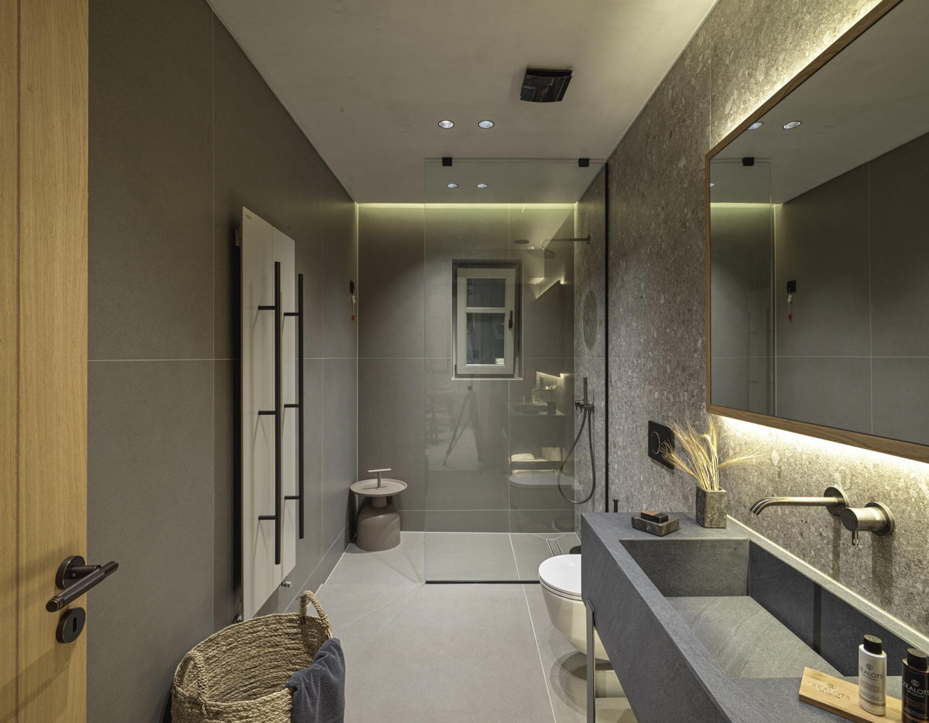 Une salle de bain moderne avec un grand miroir, une baignoire et des toilettes.