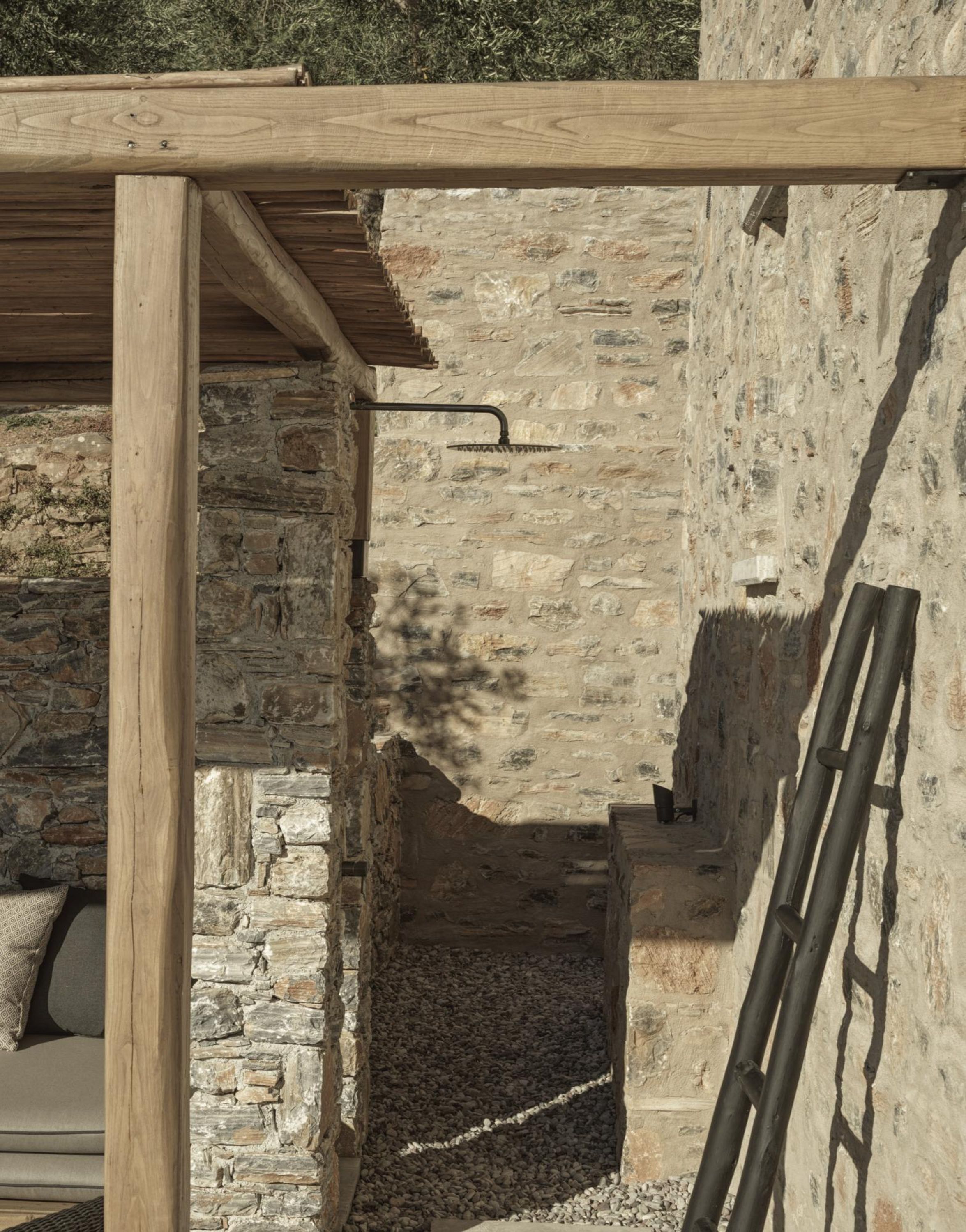 A stone-walled room with a wooden ceiling and a metal ladder leaning against the wall.