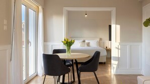 Ein modernes Hotelzimmer mit einem Bett, einem runden Tisch mit Stühlen und einer Blumenvase.