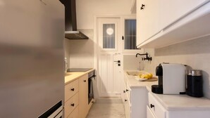 Eine kleine Küche mit Kühlschrank, Backofen und Spüle.