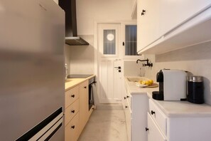 A compact kitchen with a refrigerator, oven, and sink. - Meliti Apartment in Plaka (Athina)