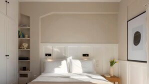 Ein ordentlich eingerichtetes Schlafzimmer mit einem großen Bett, integrierten Regalen, einem Nachttisch mit einer Vase und einem gerahmten Bild an der Wand.