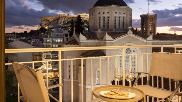 Ein Balkon mit Tisch für zwei Personen, mit Blick auf eine Stadtansicht, dominiert von einem Gebäude mit Kuppel und Glockenturm.