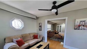 Una sala de estar con un sofá color beige, una mesa de centro de madera y un ventilador de techo.