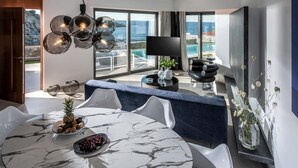 Una cocina moderna con una mesa de mármol, sillas blancas y vista al mar.