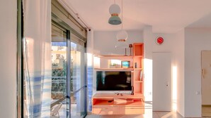 A modern living room with a large TV, wooden entertainment unit, and a balcony with a glass door. - Dizengoff Muguet in Tel Aviv-Yafo (Tel Aviv-Yafo)