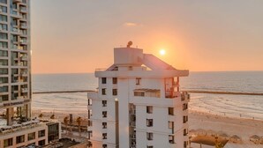 Een hoog gebouw met uitzicht op het strand en de ondergaande zon.