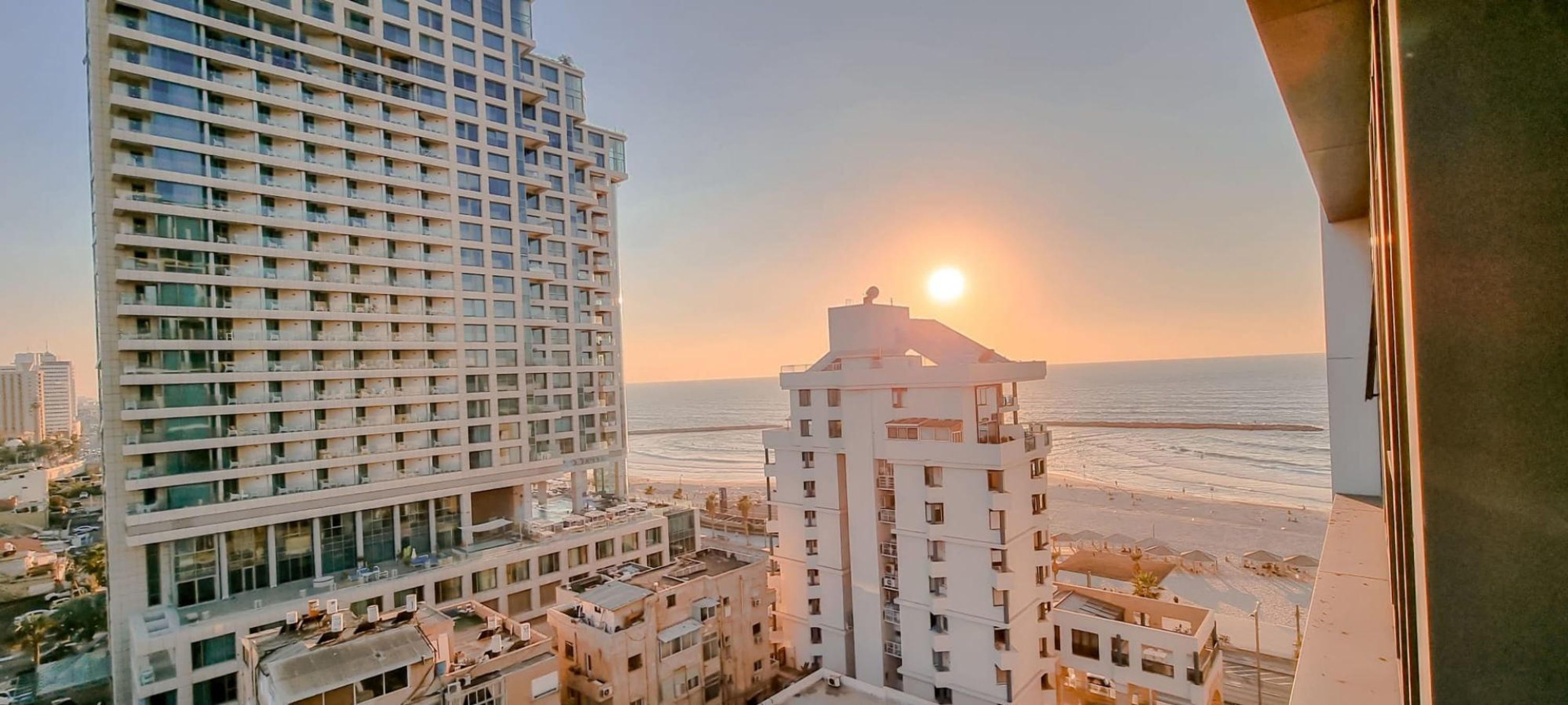 A high-rise building with a view of the ocean at sunset.