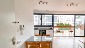Eine moderne Wohnung mit Küche, Essbereich und einem Balkon mit Fernseher.