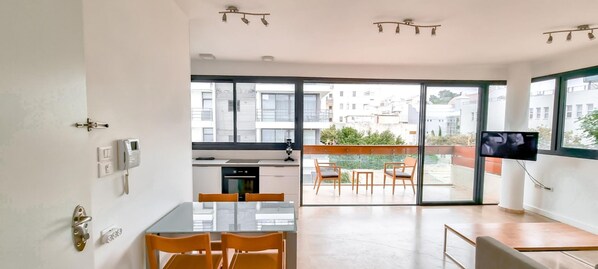 A modern apartment with a kitchen, dining area, and a balcony with a TV. - Kalisher Ophrys in Tel Aviv-Yafo (Tel Aviv-Yafo)
