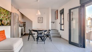 Ein modernes Apartment mit Essbereich, Küche und einem Balkon mit Blick auf die Stadt.