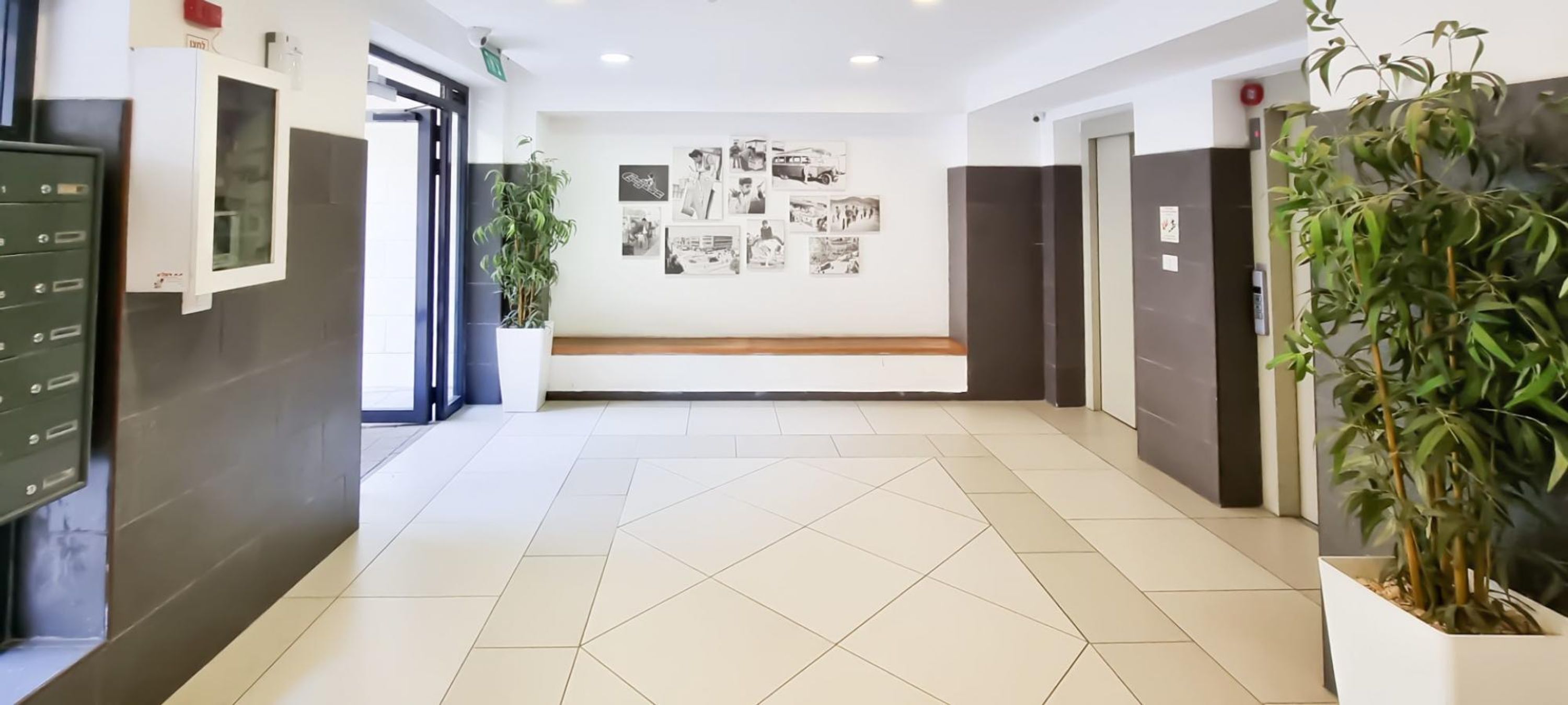 Un hall de hotel con piso de baldosas, una recepción, un banco y una pared con fotografías.
