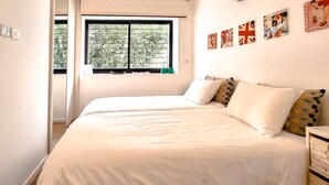A bedroom with two beds, a window with blinds, and wall decorations including flags. - Rupin Nacre in Tel Aviv-Yafo (Tel Aviv-Yafo)