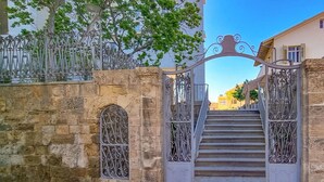 A stone gate with ornate metalwork, leading to a staircase and a building with a sign indicating '61 Eilat'. - Blanche Eilat in Tel Aviv-Yafo (Tel Aviv-Yafo)