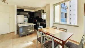 Une cuisine moderne avec un coin repas, une grande fenêtre et une vue sur le bâtiment extérieur.