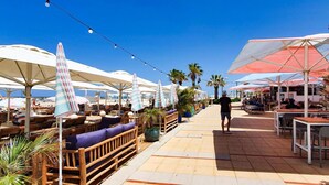 A beachside restaurant with outdoor seating, umbrellas, and palm trees. - Ramat Yam Marine in Herzliya (Tel Aviv-Yafo)