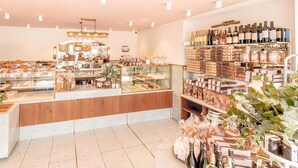 A bakery with a variety of baked goods displayed in glass cases and shelves, and a selection of wine bottles on the right side. - Ramat Yam Marine in Herzliya (Tel Aviv-Yafo)