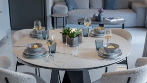 Una mesa redonda de comedor con seis sillas, rodeada por un moderno salón con un sofá y una mesa de centro.