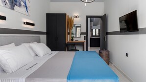 Una habitación de hotel moderna con una cama grande, un escritorio, un televisor y un cuadro en la pared.