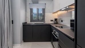 Una cocina moderna con armarios oscuros, una ventana y un refrigerador de acero inoxidable.