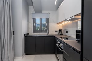 Una cucina moderna con mobili scuri, una finestra e un frigorifero in acciaio inossidabile.