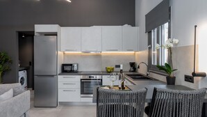 A modern kitchen with white cabinets, stainless steel appliances, and a dining area with wicker chairs. - Superior Suite with sea views to Argostoli bay (Argostoli)
