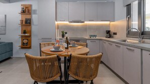 Una cocina moderna con comedor, que incluye una mesa redonda con sillas, un estante empotrado con objetos decorativos y un ventanal que proporciona luz natural.