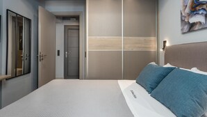 Un dormitorio moderno con una cama grande, un armario con puertas correderas y un espejo.