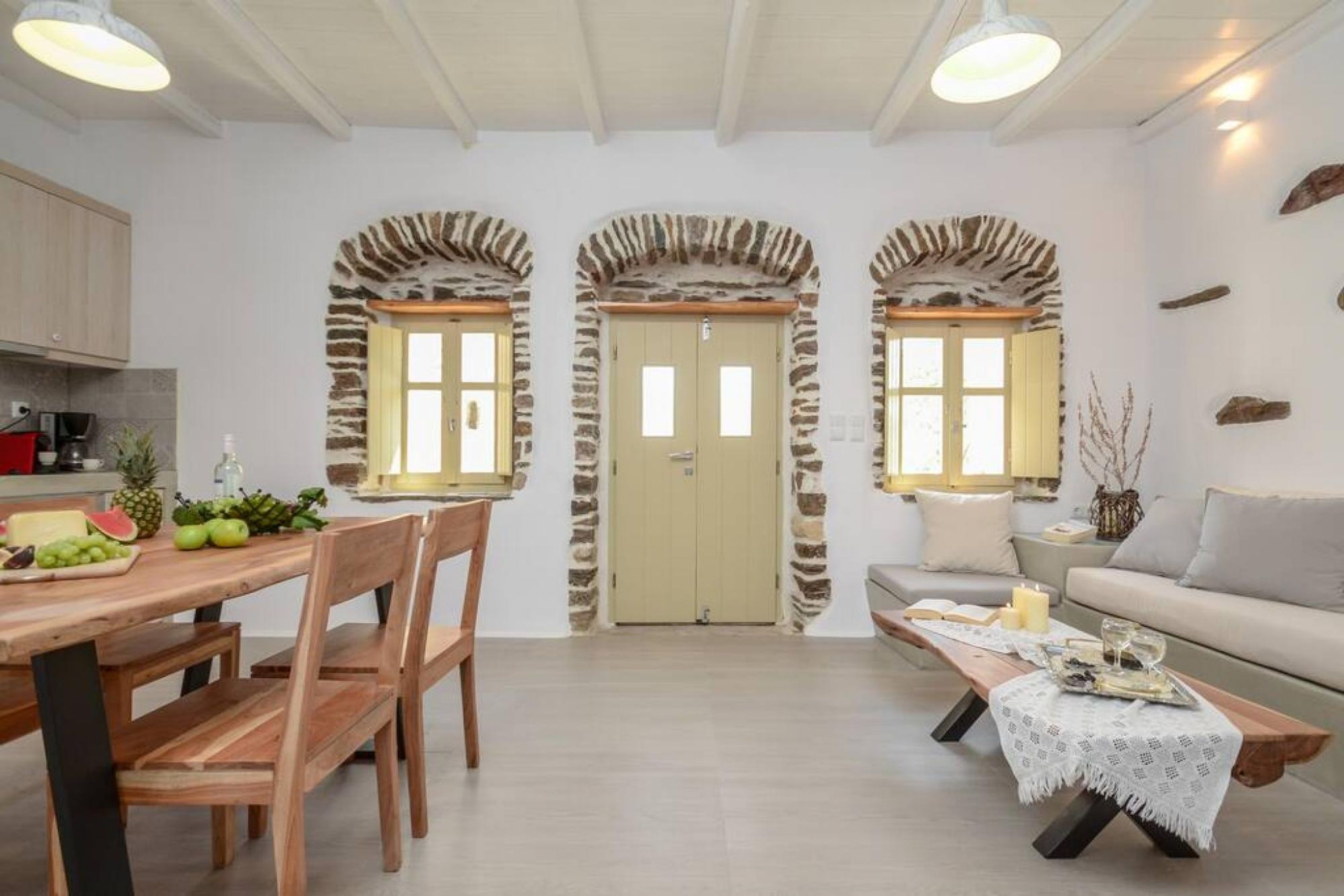 Eine moderne Küche mit Holzausstattung, einem Esstisch mit Stühlen und einem Steingewölbe, das zu einer Tür führt.