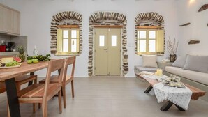 Uma cozinha moderna com armários de madeira, uma mesa de jantar com cadeiras e um arco de pedra que dá acesso a uma porta.