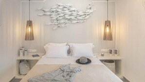 Ett modernt hotellrum med en stor säng, två sängbord, en väggdekoration med fiskmotiv och hängande lampor.