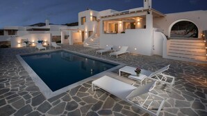 A modern villa with a swimming pool, outdoor seating, and a stone patio. - Villa Agali Naxos Glyfada Kastraki (Naxos)