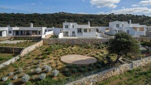 A modern white villa with a spacious patio, surrounded by a landscaped garden and a stone wall. - Villa Agali Naxos Glyfada Kastraki (Naxos)