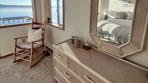 A bedroom with a large mirror, a wooden rocking chair, a dresser, and a view of the lake. - Fox Island Beachfront Retreat - Kayaks, Canoe, Paddle Board & Epic Sunsets (Fox Island)