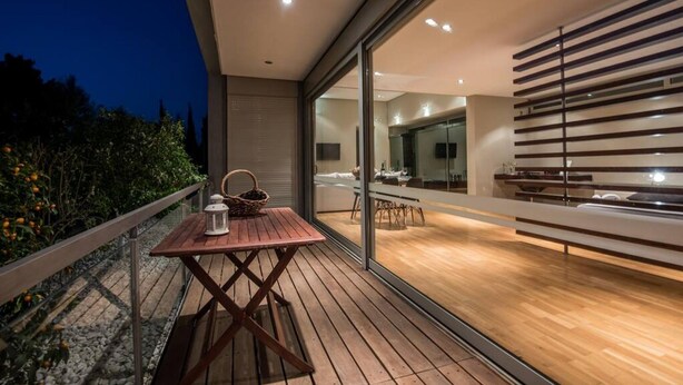 A modern outdoor patio with a wooden table and chairs, a wicker basket, and a lantern. - Studio Rio: Unique space with garden and garage (Ρίο)