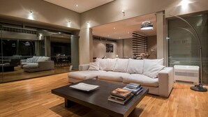 A modern living room with a sectional sofa, a coffee table, and a large mirror. - Studio Rio: Unique space with garden and garage (Ρίο)