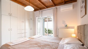 Ein Schlafzimmer mit zwei Betten, einem Fenster mit Vorhängen, einem Heizkörper und einem Deckenventilator.