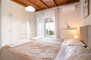 A bedroom with two beds, a window with curtains, a radiator, and a ceiling fan. - Villa ChrisDina in Nymfes (Nymfes)