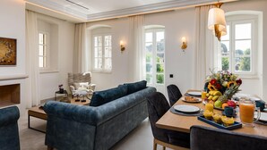 Un coin repas moderne avec une table en bois mise pour le petit-déjeuner, comprenant des fruits, des viennoiseries et une carafe de jus d’orange.