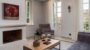 Un salon moderne doté d’une cheminée, d’un fauteuil confortable, d’un canapé et offrant une vue sur la ville grâce à de grandes fenêtres.