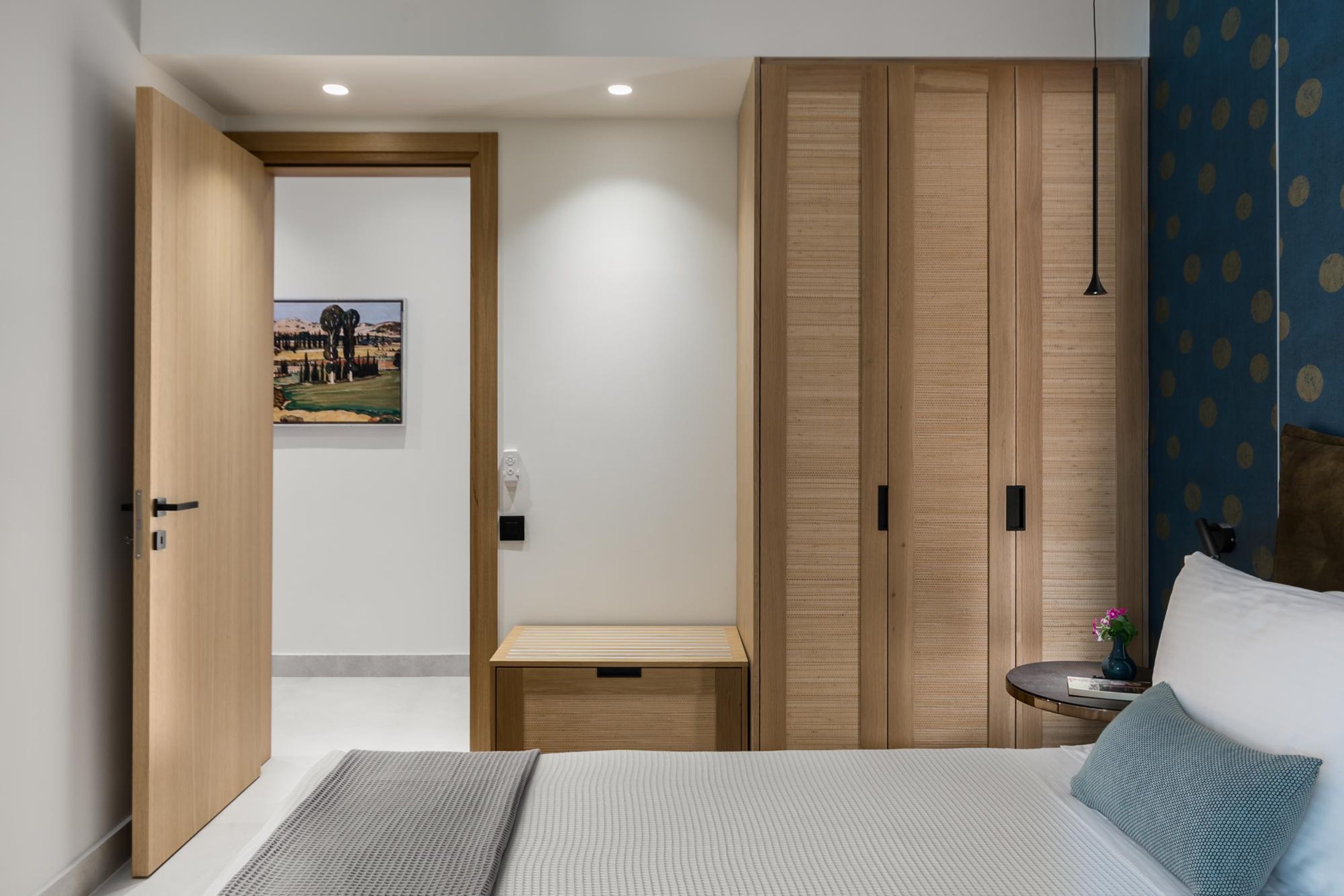 Une chambre à coucher comprenant un lit, une armoire en bois, une table de chevet et une commode.