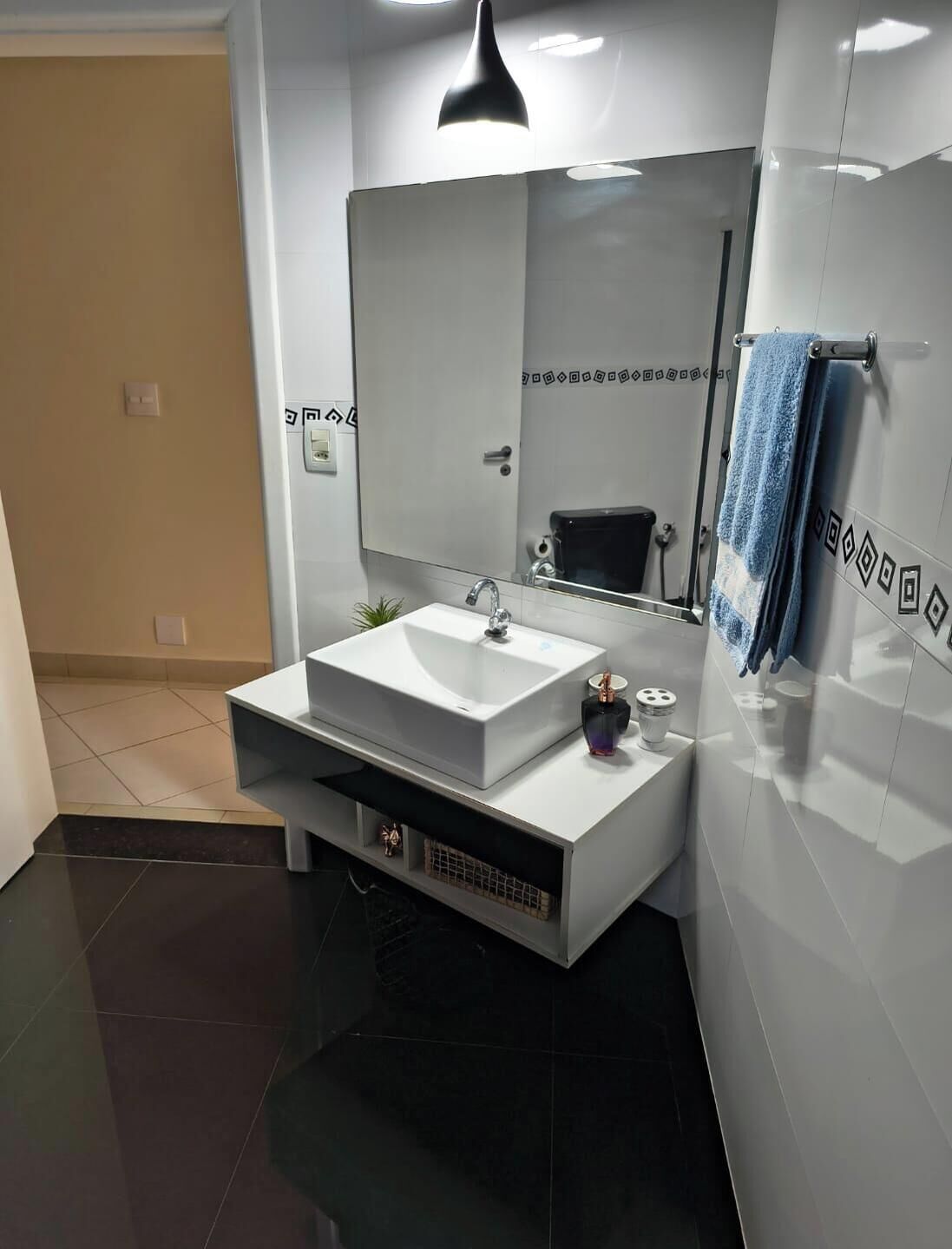A modern bathroom with a white sink, a large mirror, and a towel rack.