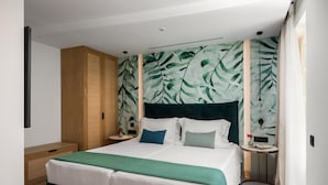 A modern bedroom with a large bed, a wooden wardrobe, a nightstand, and a wall with a leafy pattern. - Penthouse Suite Sea View (Kerkira)